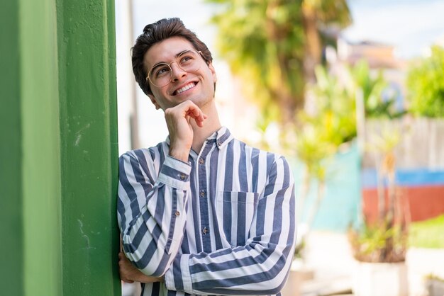 Jovem bonito com óculos e pensando enquanto olha para cima