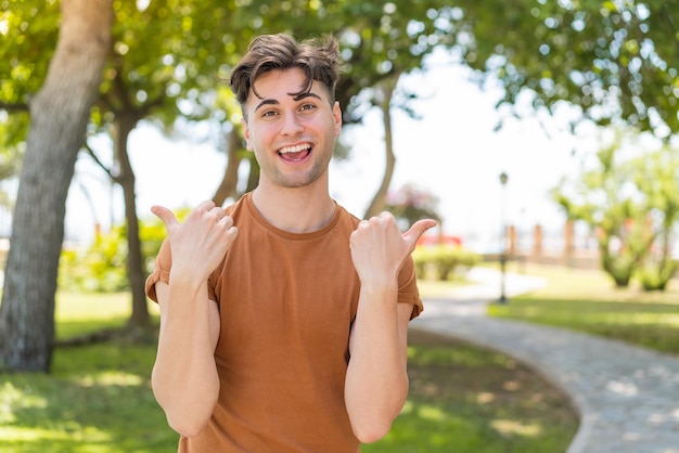 Jovem bonito com polegares para cima gesto e sorrindo