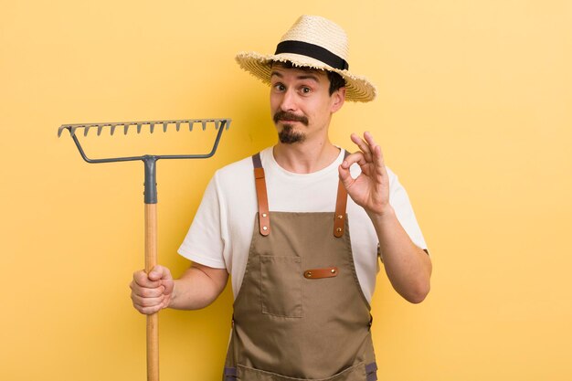 Jovem bonito com um conceito de agricultor de ancinho