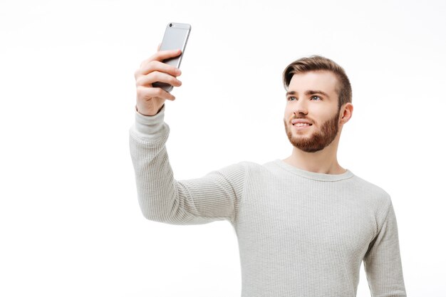 Jovem bonito com um suéter branco usando o telefone