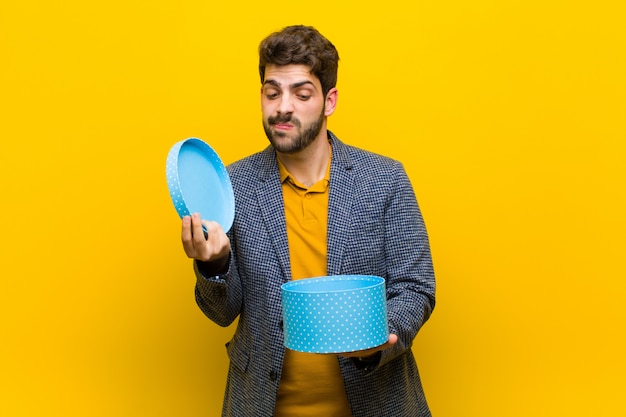 Jovem bonito com uma caixa contra fundo laranja