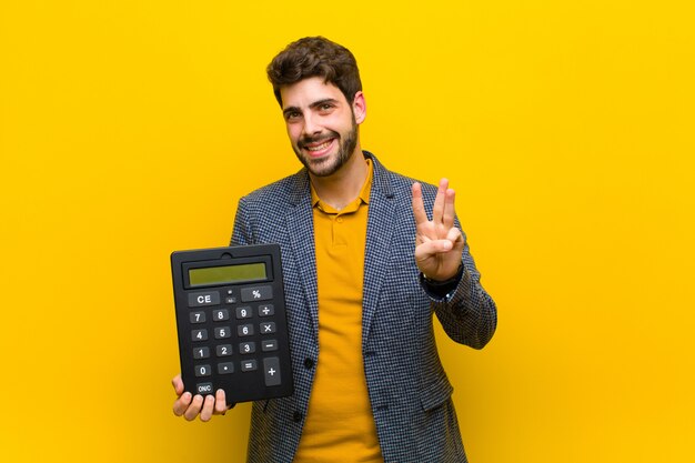 Jovem bonito com uma calculadora na laranja