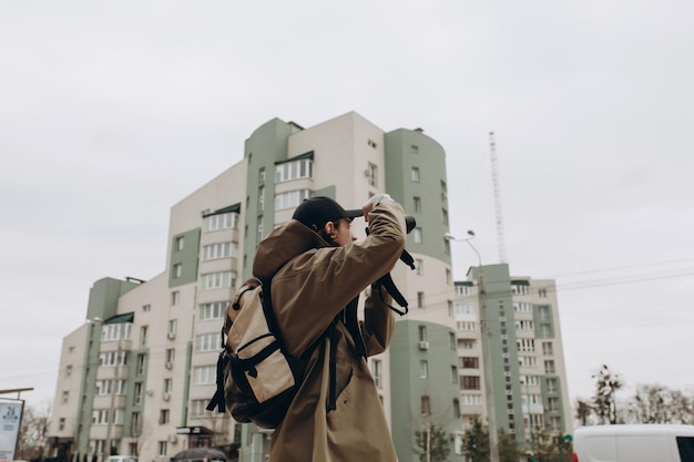 Jovem bonito com uma câmera profissional no fundo de um prédio de apartamentos