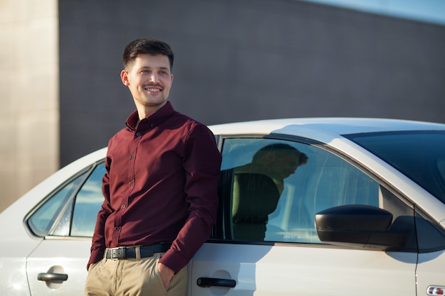 jovem bonito com uma camisa em pé perto de um carro