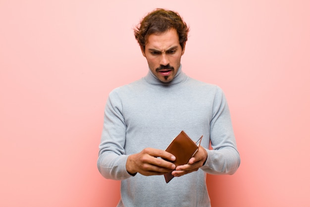 Jovem bonito com uma carteira contra parede plana-de-rosa