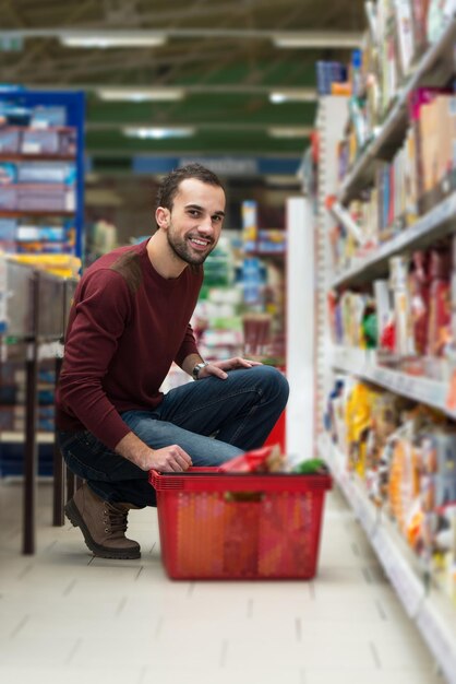 Jovem bonito comprando frutas e legumes no departamento de produtos de uma mercearia supermercado raso de campo