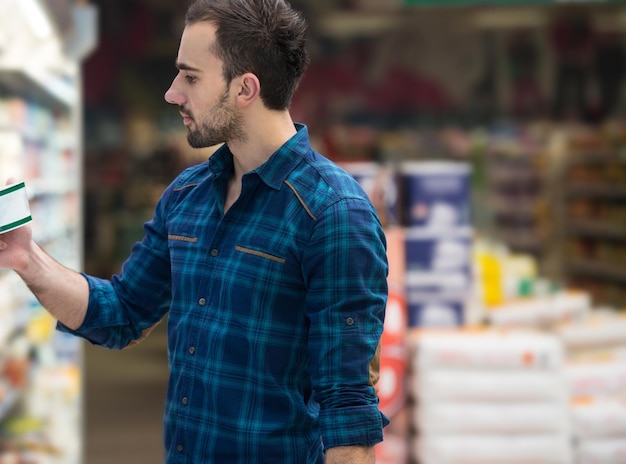 Jovem bonito comprando frutas e legumes no departamento de produtos de uma mercearia supermercado raso de campo