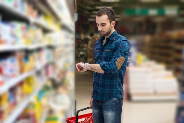 Jovem bonito comprando frutas e legumes no departamento de produtos de uma mercearia supermercado raso de campo