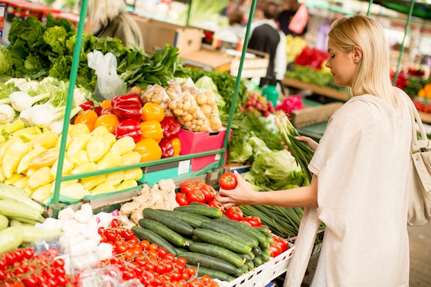 Jovem bonito comprando legumes no mercado