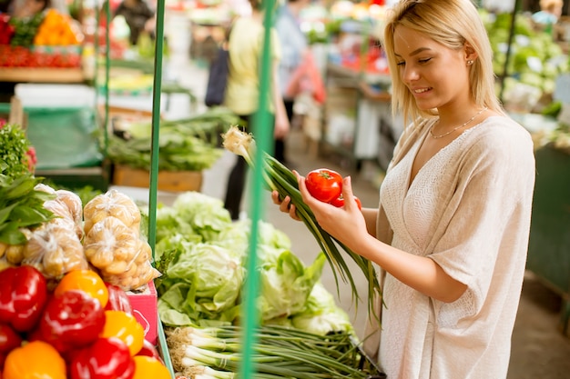 Jovem bonito comprando legumes no mercado