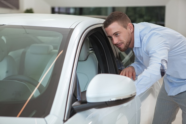 Jovem bonito comprando um carro novo no salão da concessionária