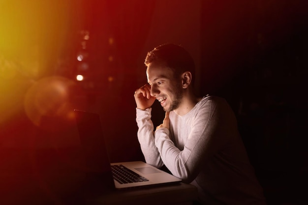 Jovem bonito confiante em olhar casual para laptop e sorrir