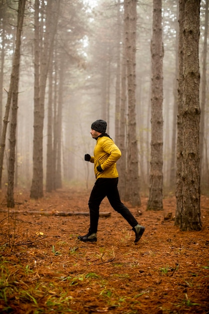 Jovem bonito correndo na floresta de outono e se exercitando para a maratona de corrida em trilha