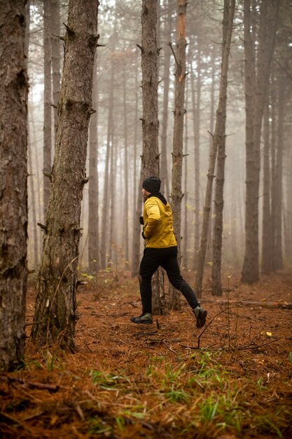 Jovem bonito correndo na floresta de outono e se exercitando para a maratona de corrida em trilha