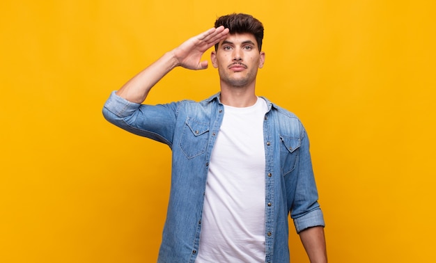 Jovem bonito cumprimentando com uma saudação militar em um ato de honra e patriotismo, mostrando respeito