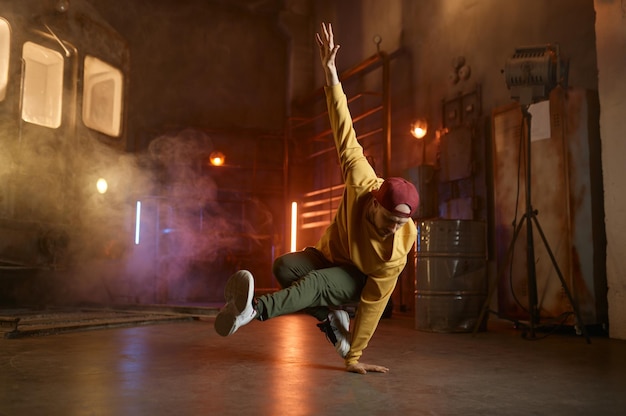 Jovem bonito dançando movimentos de hip hop breakdancing sobre fundo de estúdio urbano