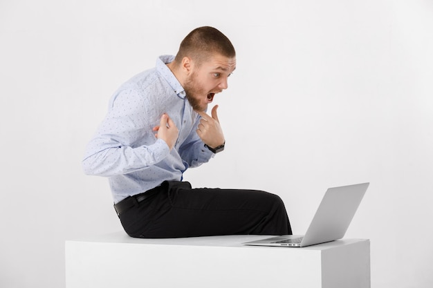 Jovem bonito de camisa e gravata usando laptop