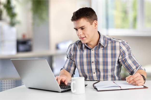 Jovem bonito de óculos usando laptop