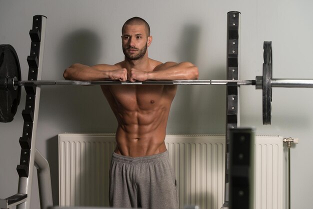 Jovem bonito e atraente com corpo musculoso relaxante no ginásio