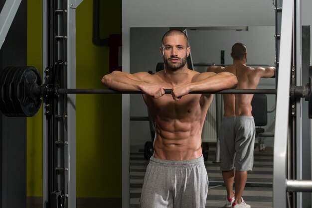 Jovem bonito e atraente com corpo musculoso relaxante no ginásio