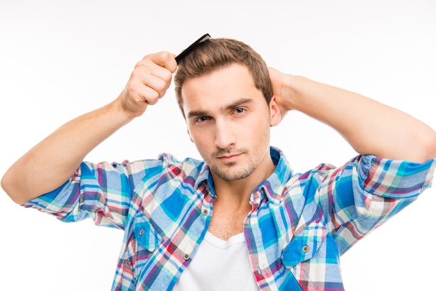 Jovem bonito e confiante penteando o cabelo