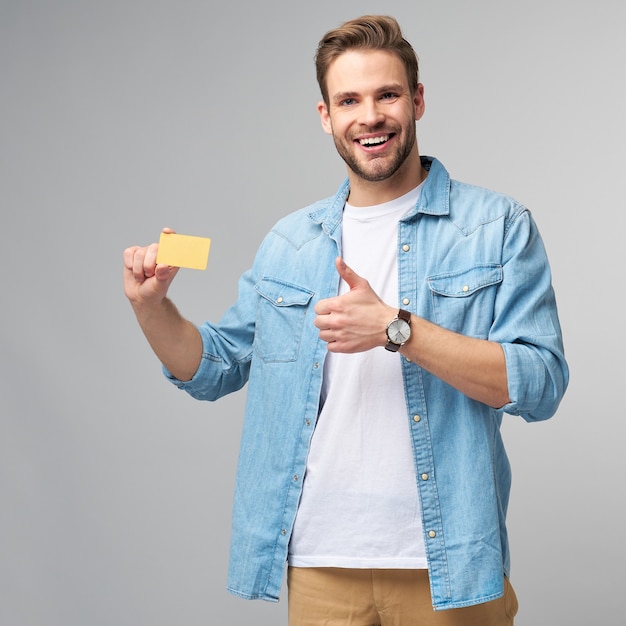 Jovem bonito e feliz mostrando cartão de desconto de banco em branco