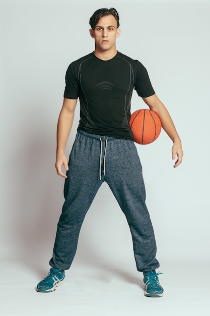 Jovem bonito e sorridente carregando uma bola de basquete