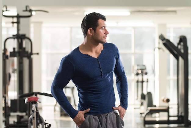 Jovem bonito em pé forte em camiseta azul e músculos flexionados Muscular Atlético Bodybuilder Fitness modelo posando após exercícios