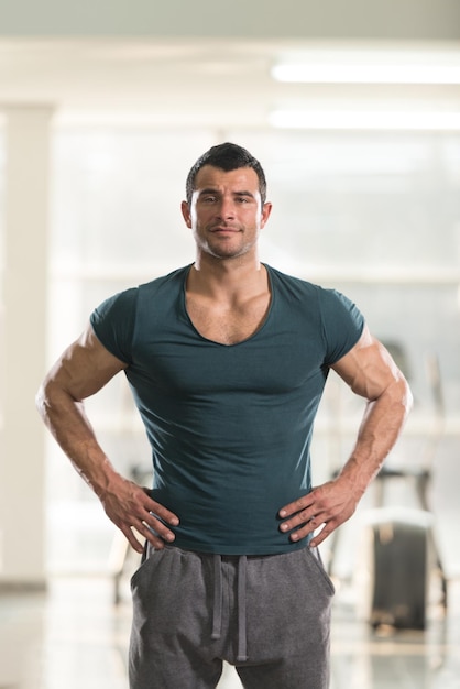 Foto jovem bonito em pé forte em camiseta verde e músculos flexionados muscular atlético bodybuilder fitness modelo posando após exercícios
