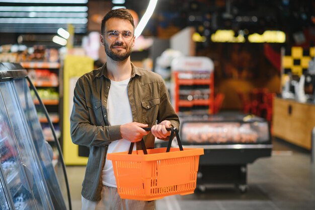 Jovem bonito escolhendo comida no supermercado