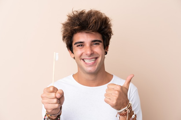 Jovem bonito, escovar os dentes com os polegares para cima, porque algo de bom aconteceu