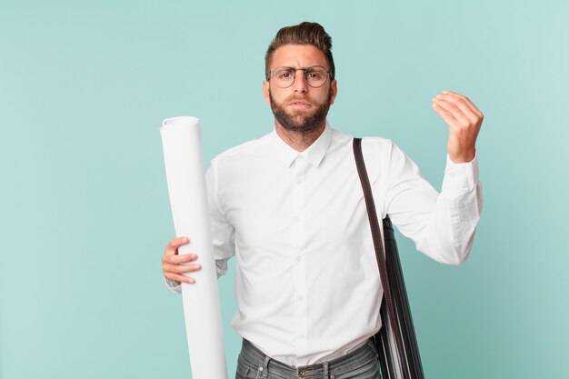 Jovem bonito fazendo capice ou gesto de dinheiro, dizendo para você pagar. conceito de arquiteto