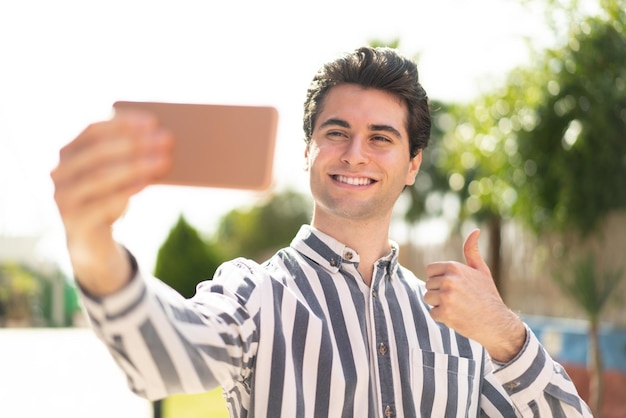 Jovem bonito fazendo uma selfie com telefone celular