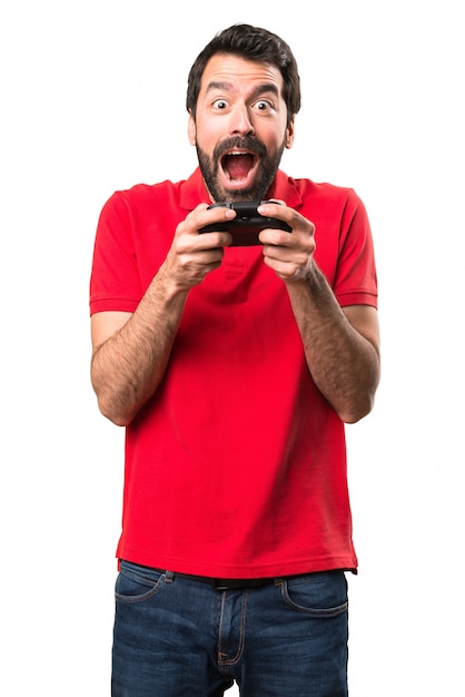 Jovem bonito feliz jogando videogames sobre fundo branco isolado