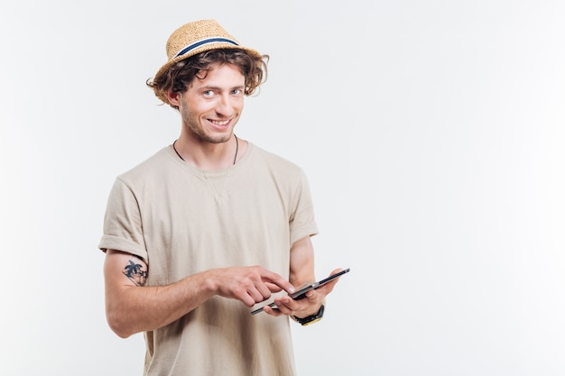 Jovem bonito feliz usando tablet e olhando para a câmera sobre fundo branco