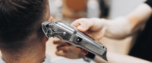 Jovem bonito feliz visitando o cabeleireiro em um salão de barbearia