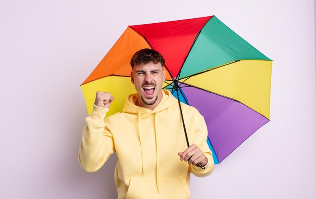 Jovem bonito gritando agressivamente com uma expressão de raiva. conceito de guarda-chuva