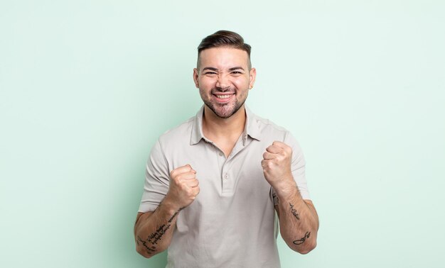 Jovem bonito gritando triunfantemente, rindo e se sentindo feliz e animado enquanto celebra o sucesso