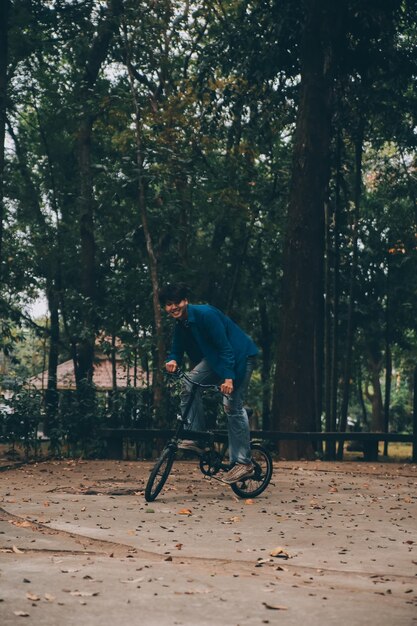 Jovem bonito homem barbudo fazendo uma pausa enquanto viaja pela cidade com sua bicicleta usando seu tablet digital olhando para longe pensativo