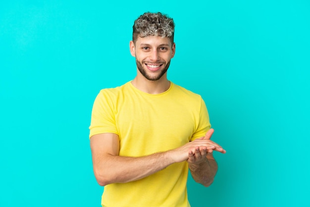 Jovem bonito homem caucasiano isolado em um fundo azul aplaudindo