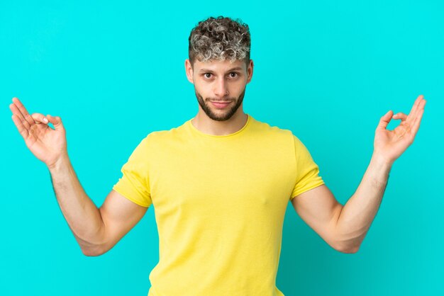 Jovem bonito homem caucasiano isolado em um fundo azul em pose zen