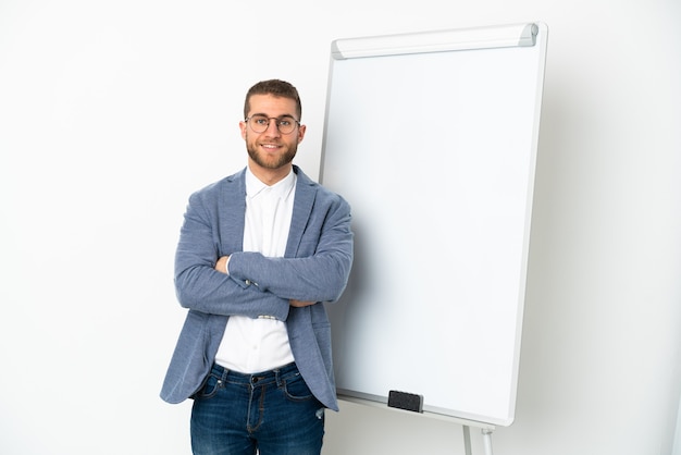 Jovem bonito homem caucasiano isolado no fundo branco fazendo uma apresentação no quadro branco e sorrindo