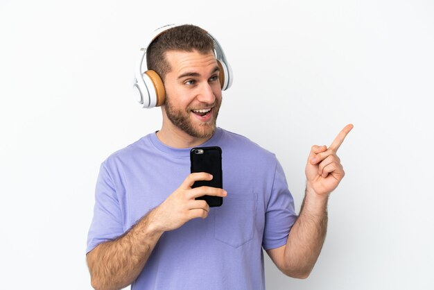 Jovem bonito homem caucasiano isolado ouvindo música com um celular e cantando