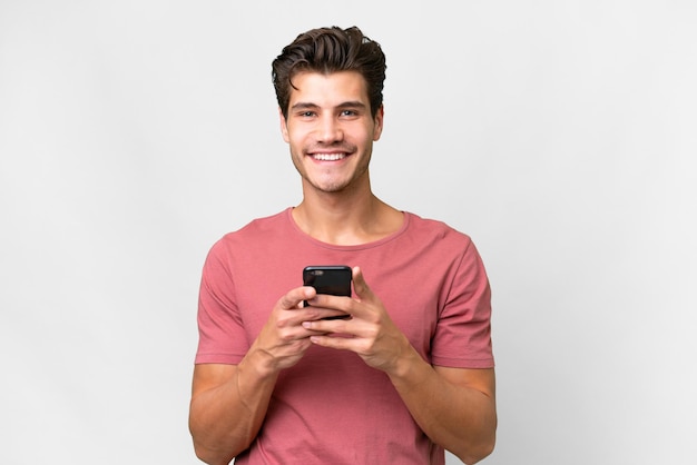 Jovem bonito homem caucasiano sobre fundo branco isolado, enviando uma mensagem com o celular