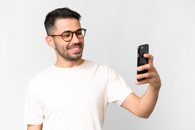 Jovem bonito homem caucasiano sobre fundo branco isolado, fazendo uma selfie