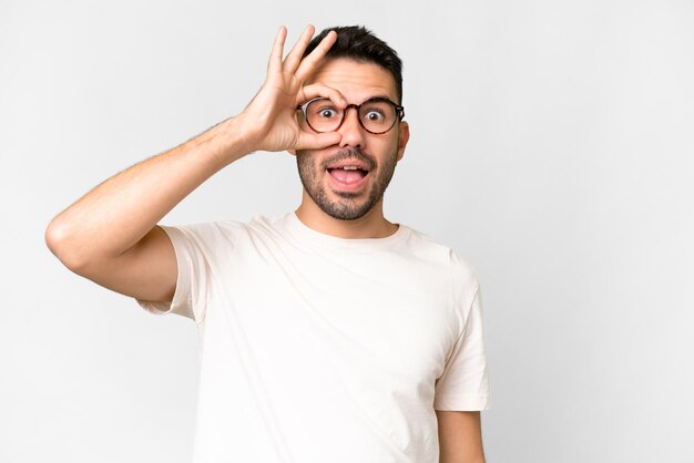 Foto jovem bonito homem caucasiano sobre fundo branco isolado, mostrando sinal de ok com os dedos