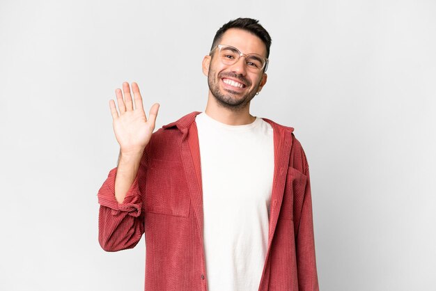 Jovem bonito homem caucasiano sobre fundo branco isolado, saudando com a mão com expressão feliz