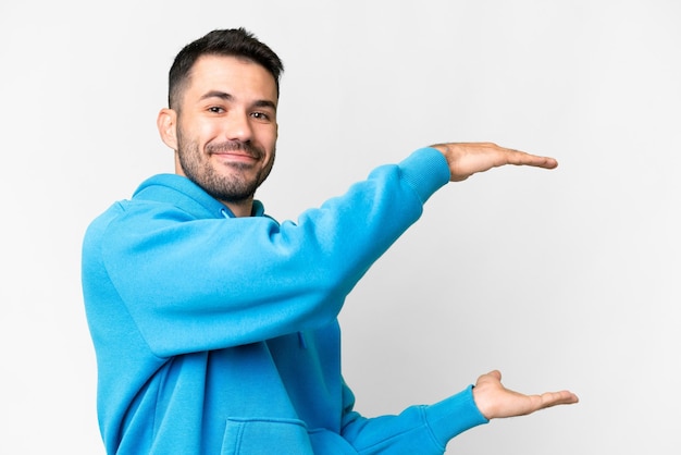 Jovem bonito homem caucasiano sobre fundo branco isolado, segurando o copyspace para inserir um anúncio