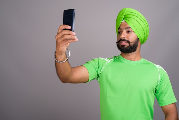 Jovem bonito indiano Sikh tirando uma selfie com o celular