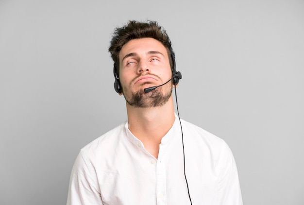 Jovem bonito isolado com fones de ouvido do operador e conceito de micro telemarketing